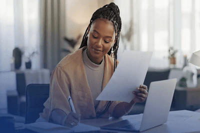 A woman at her desk working on physical and digital application templates