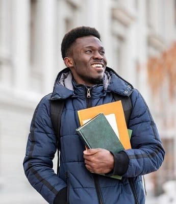 Student outside with books preparing for scholarship application